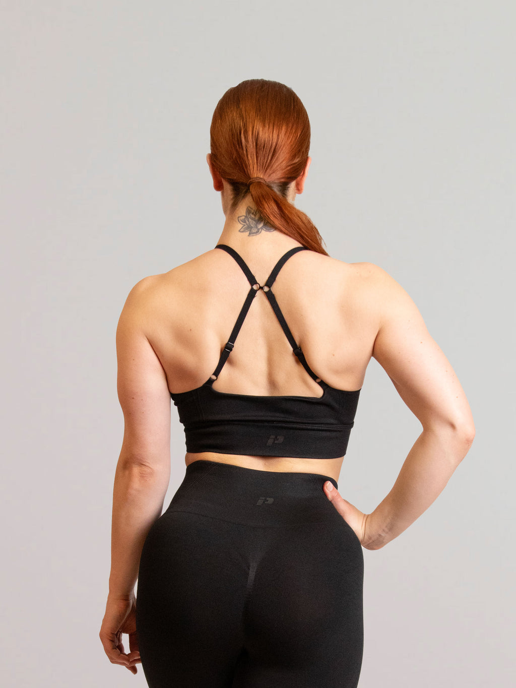 Camille de dos portant la brassière de sport noir et le legging de sport noir inprocess